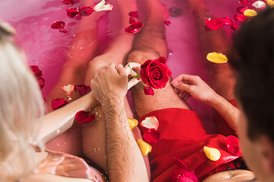 Women giving red rose to man in the bath tub to have sensual massage